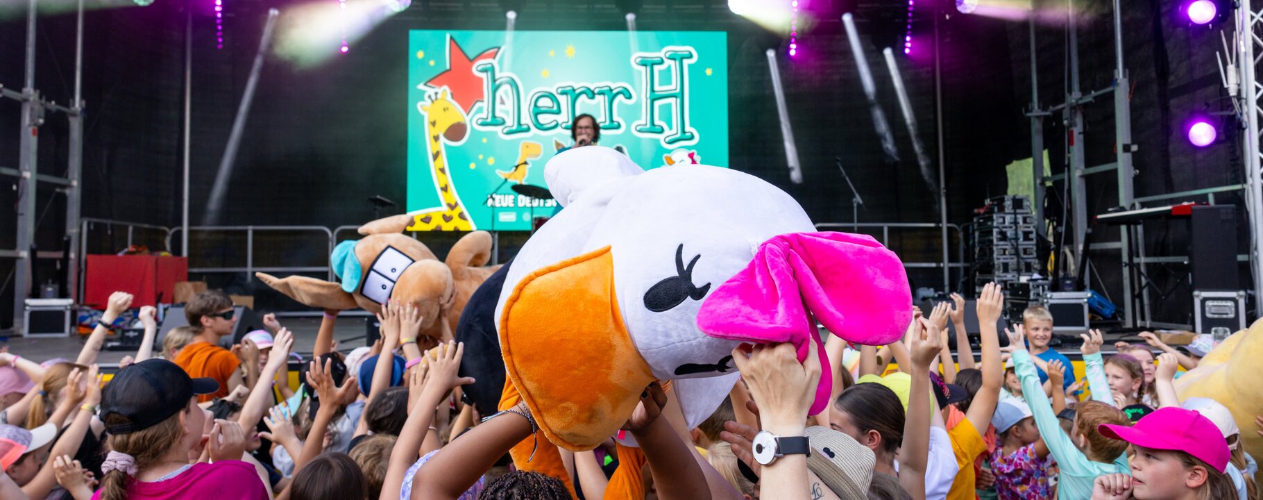 HerrH begeistert Kinder beim Mounds Festival mit Mitmach-Show | © Serfaus-Fiss-Ladis Marketing GmbH | Fabian Schirgi HerrH live auf der Bühne beim Mounds Festival, Kinder tanzen und feiern mit großen Kuscheltieren vor der Bühne. | © Serfaus-Fiss-Ladis Marketing GmbH | Fabian Schirgi