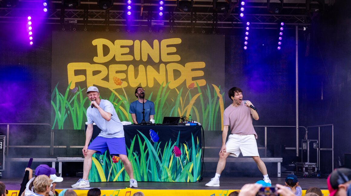 Zwei Moderatoren performen Musik auf einer Kinderveranstaltung.