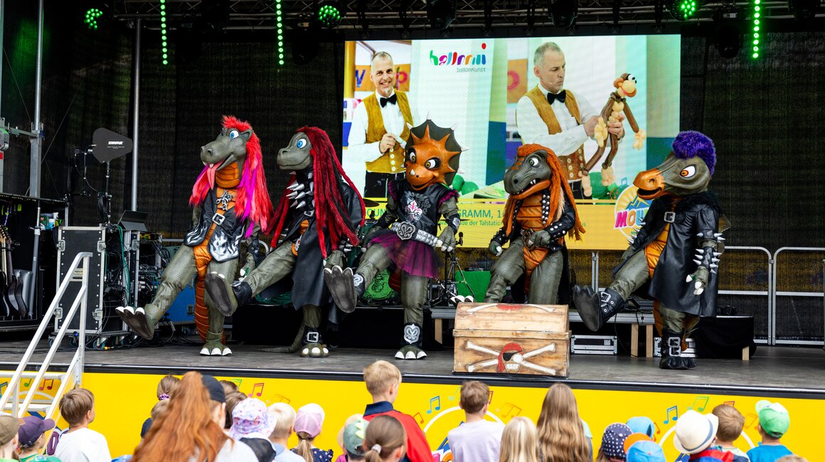Puppenspieler in Tierkostümen unterhalten Kinder auf einer Bühne.