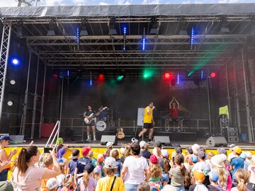 Eine Band spielt ein Konzert für Kinder; viele Fans schauen zu.
