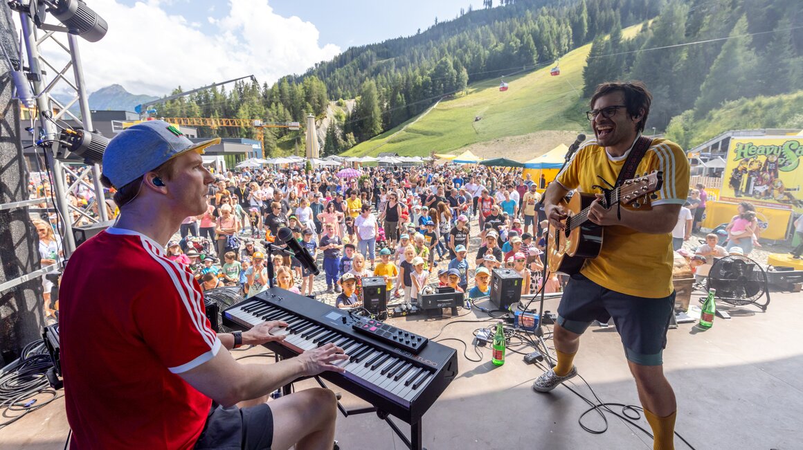 Zwei Musiker spielen vor begeistertem Publikum in den Bergen.