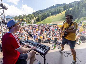 Zwei Musiker spielen vor begeistertem Publikum in den Bergen.