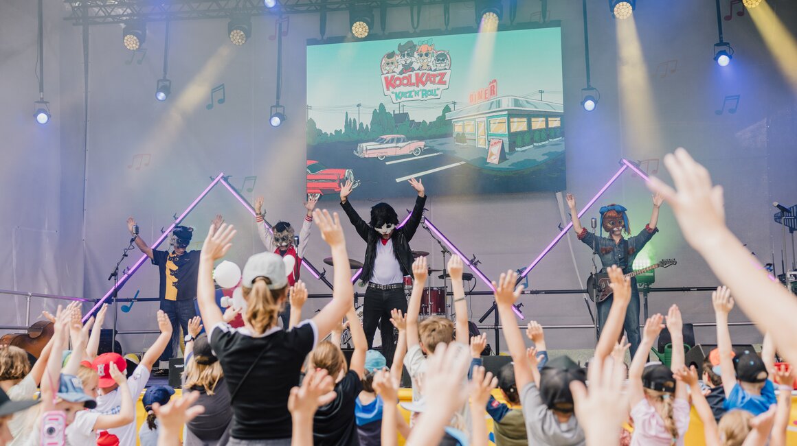 Kinder jubeln beim KoolKatz Live-Konzert auf der Bühne.