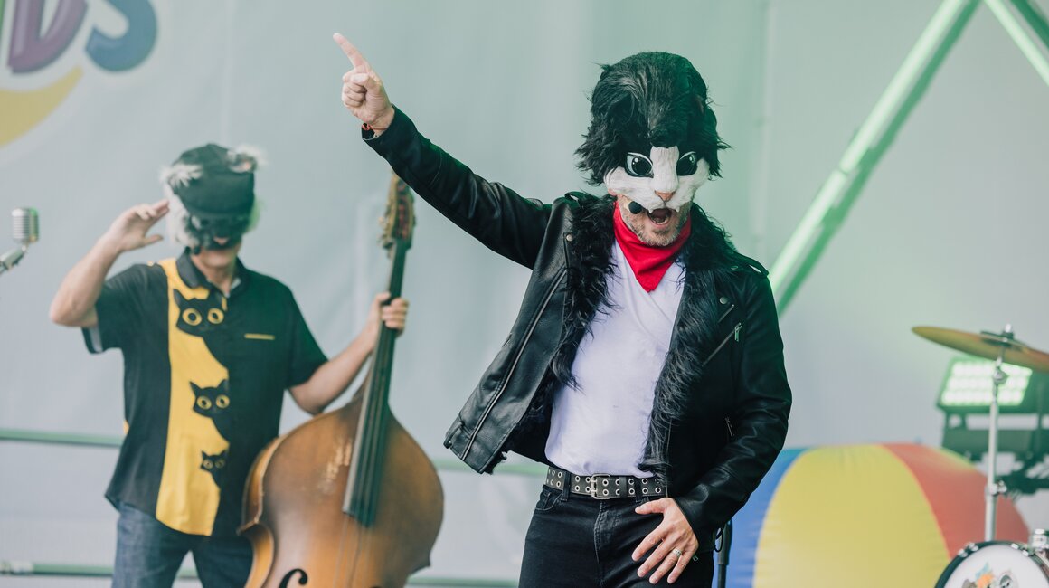 Zwei Musiker in Katzenmasken bei einem Auftritt, einer singt, der andere spielt Kontrabass.