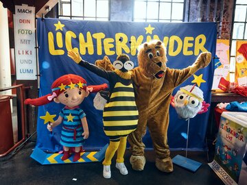Kindercharaktere und ein Bär posieren für ein Foto.