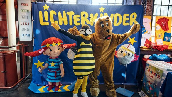 Kindercharaktere und ein Bär posieren für ein Foto.