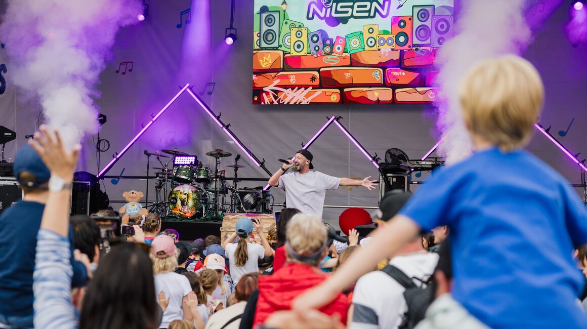 Ein Künstler performt live vor einer energiegeladenen Menge von Kindern.