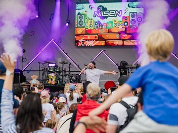 Ein Künstler performt live vor einer energiegeladenen Menge von Kindern.
