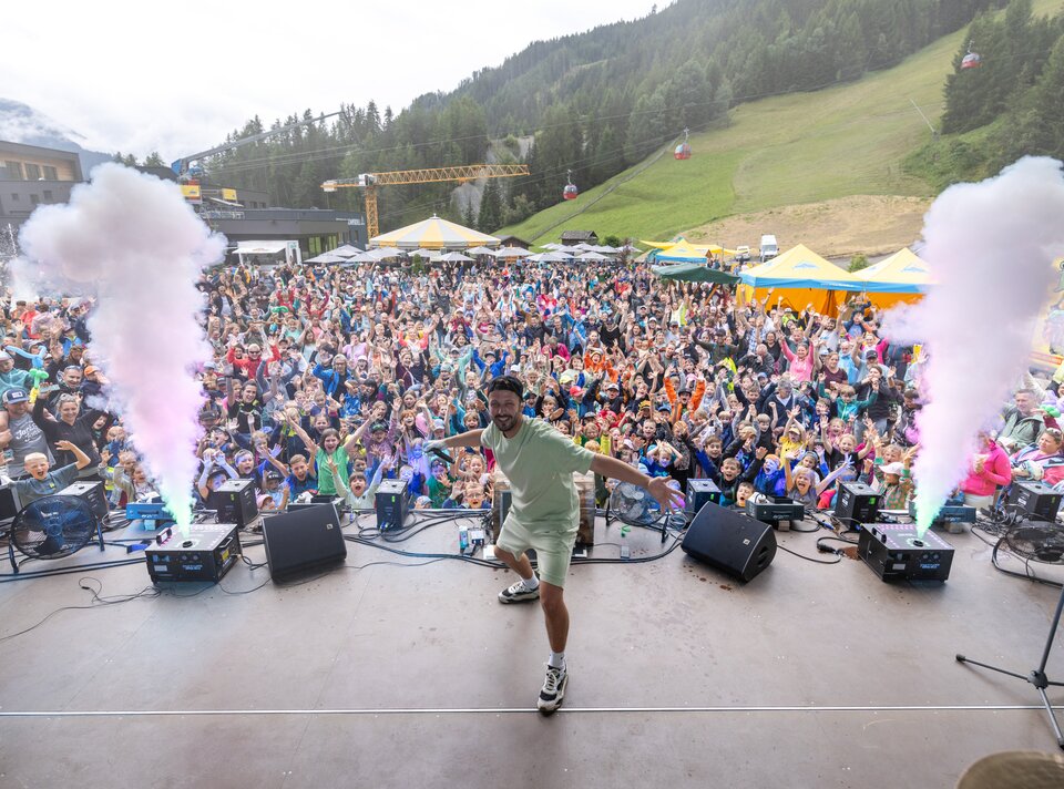 Ein Performer begeistert eine große Menge mit buntem Licht und Rauch.