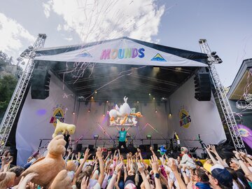 Bühne des Mounds Festivals mit jubelnden Menschen und Luftballons.