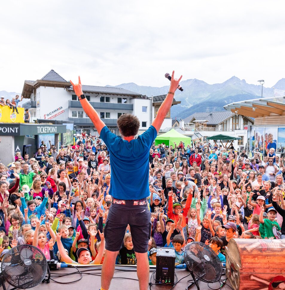 Ein Performer animiert eine große Menschenmenge bei einem Event.