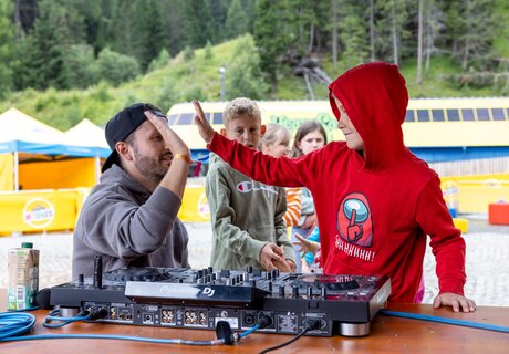 Ein DJ interagiert mit Kindern, während sie Spaß am Musikmachen haben.