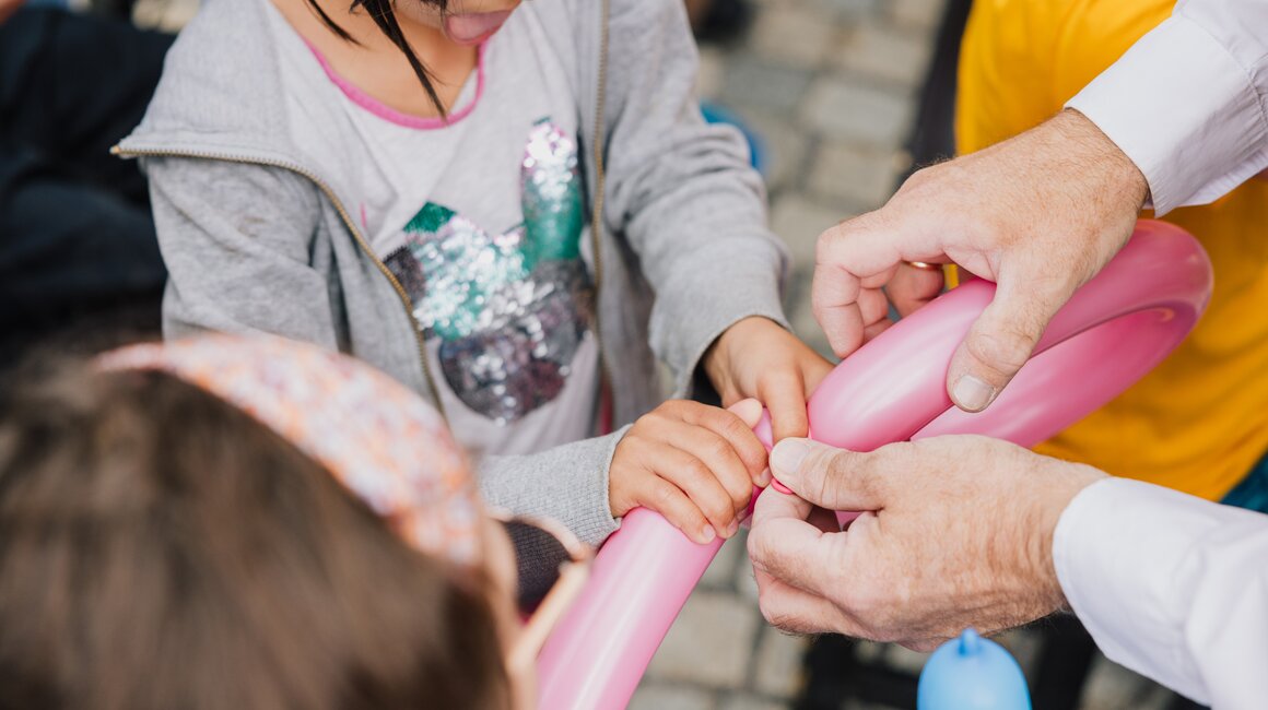 Kinder halten und formen Ballons mit Hilfe eines Erwachsenen.