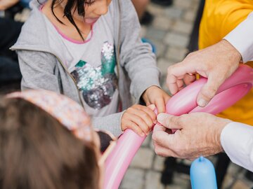Kinder halten und formen Ballons mit Hilfe eines Erwachsenen.
