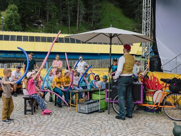 Eine Gruppe Kinder mit Luftballons hört einem Animateur zu.