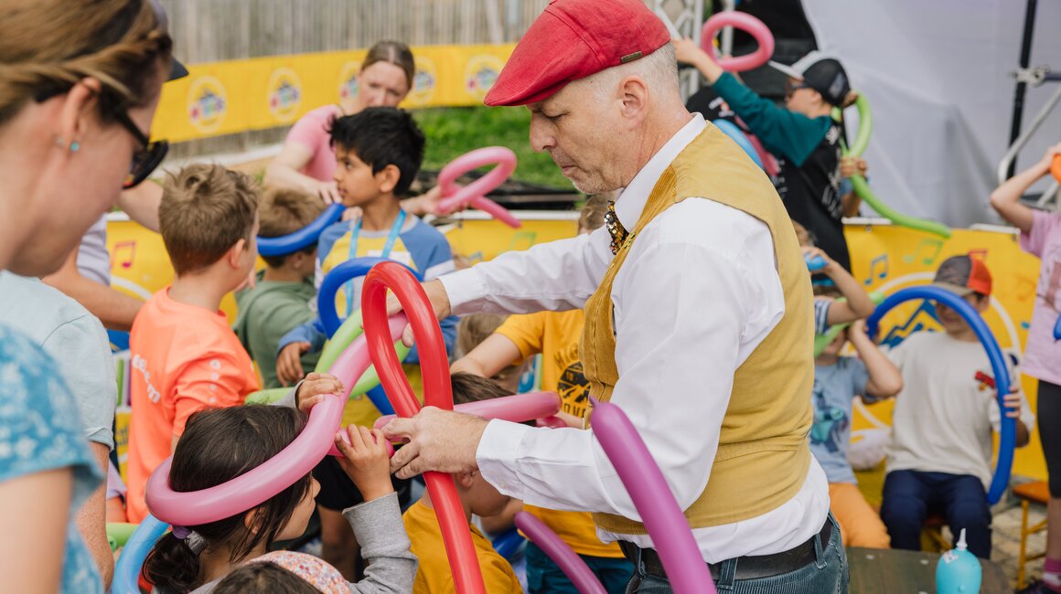 Kinder kreieren mit Luftballons zusammen mit einem unterhaltsamen Veranstalter.