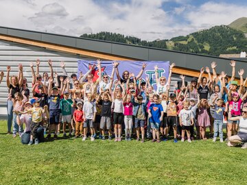 Fröhliche Kinder und Erwachsene posieren gemeinsam im Freien.