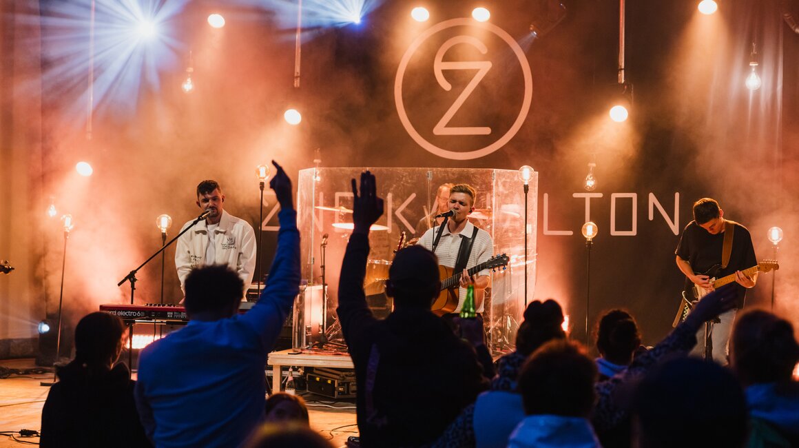 Band spielt live auf der Bühne, das Publikum reagiert begeistert.