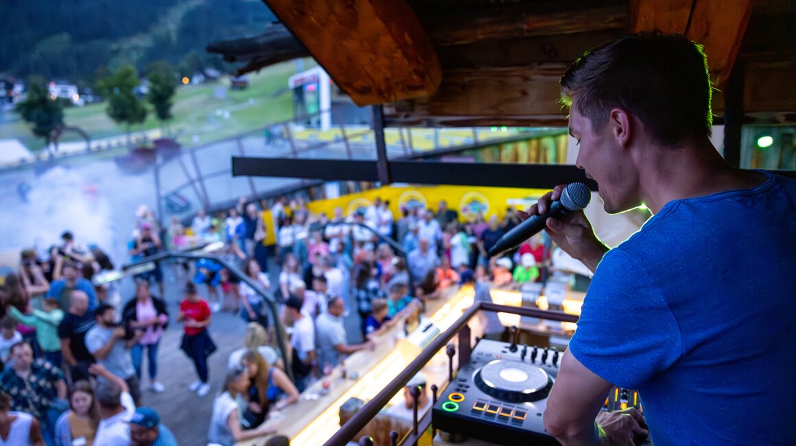 Ein DJ spielt Musik für eine große Menschenmenge im Freien.