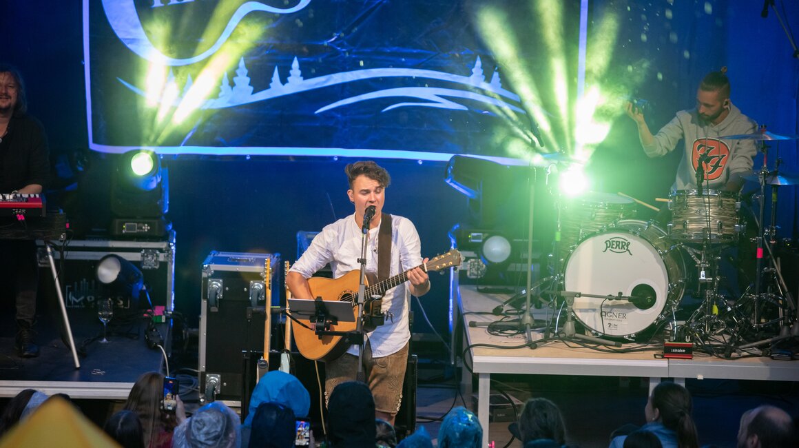 Chris Tegner mit Gitarre live auf der Bühne, Publikum blickt zu ihm.