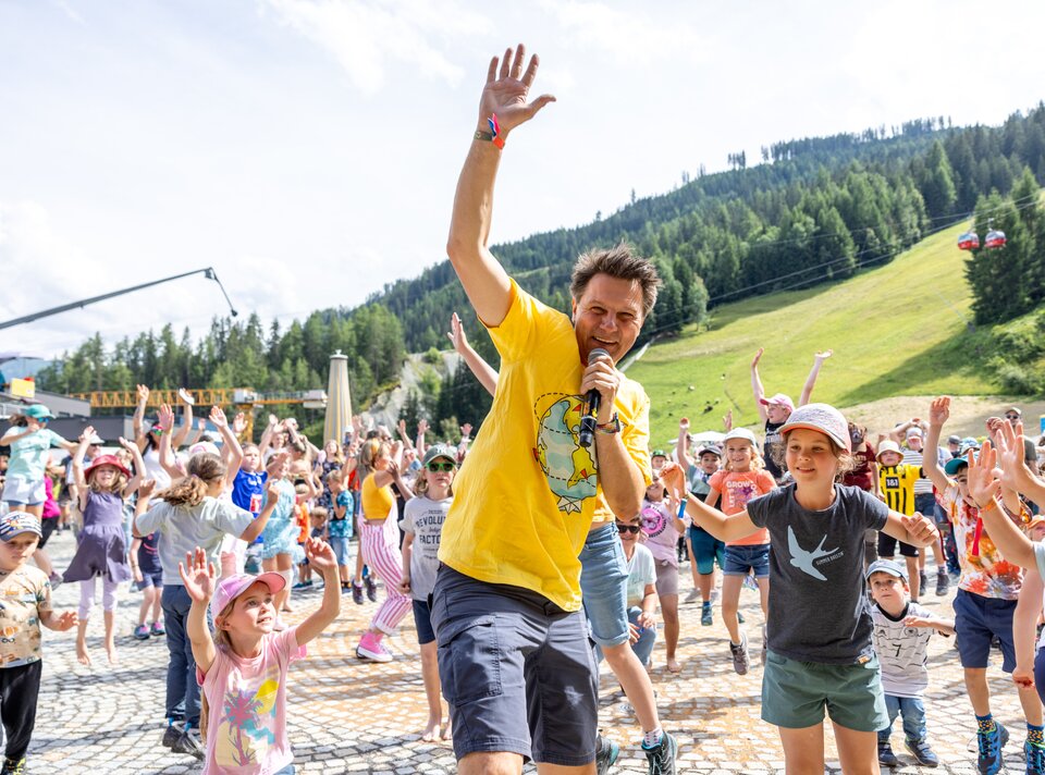 Ein Mann animiert eine Gruppe von Kindern in der Natur.