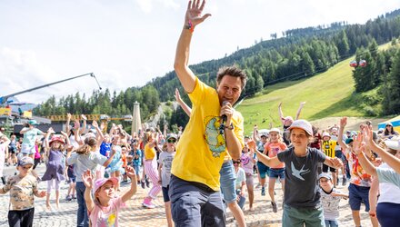 Ein Mann animiert eine Gruppe von Kindern in der Natur.