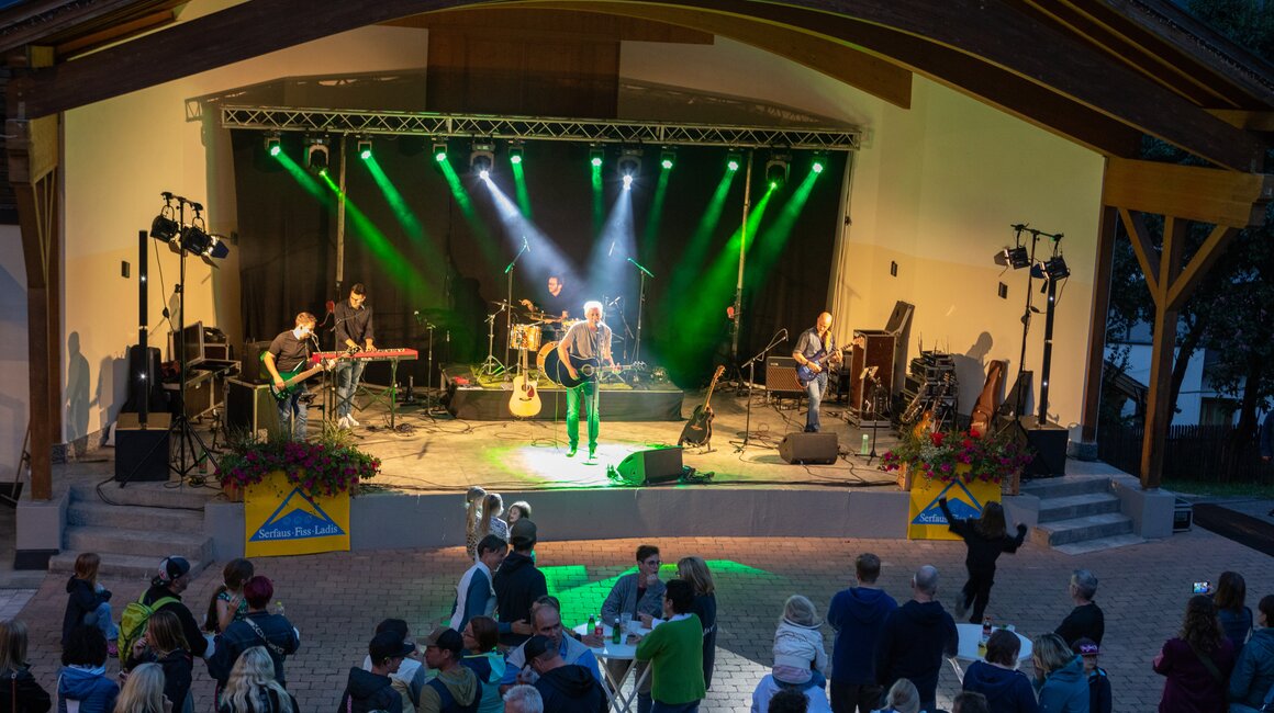 Band spielt live; Publikum genießt das Konzert unter freiem Himmel.