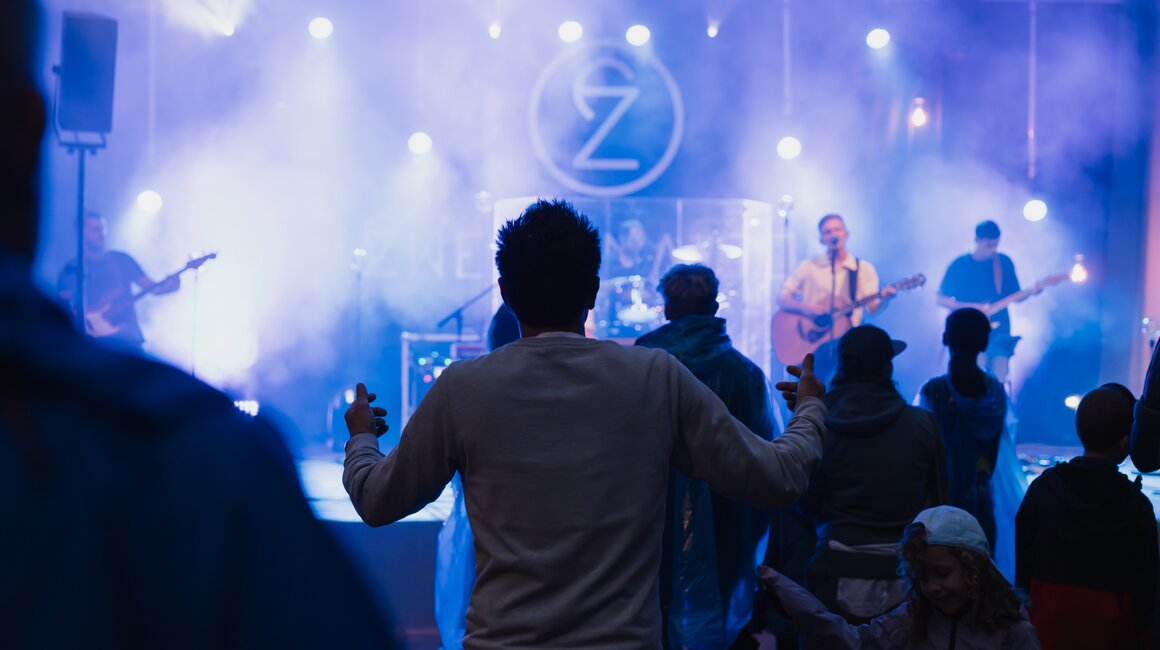 Zuschauer tanzen und feiern beim Live-Konzert, Lichteffekte im Hintergrund.