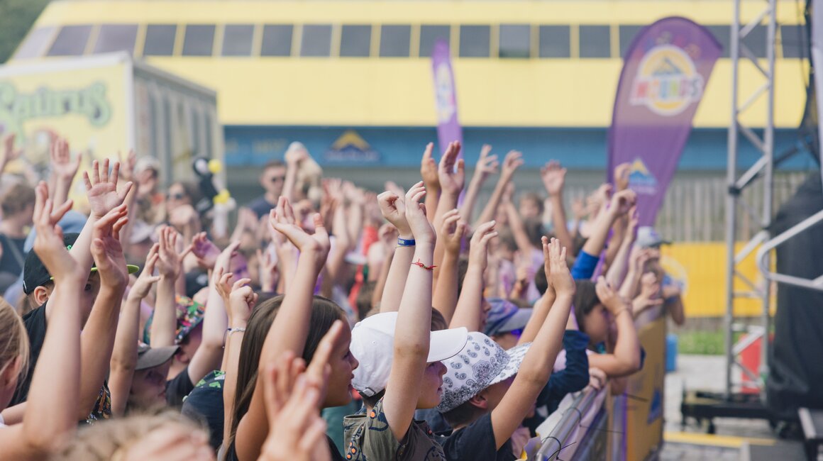 Menschen mit erhobenen Händen feiern ein Konzert.