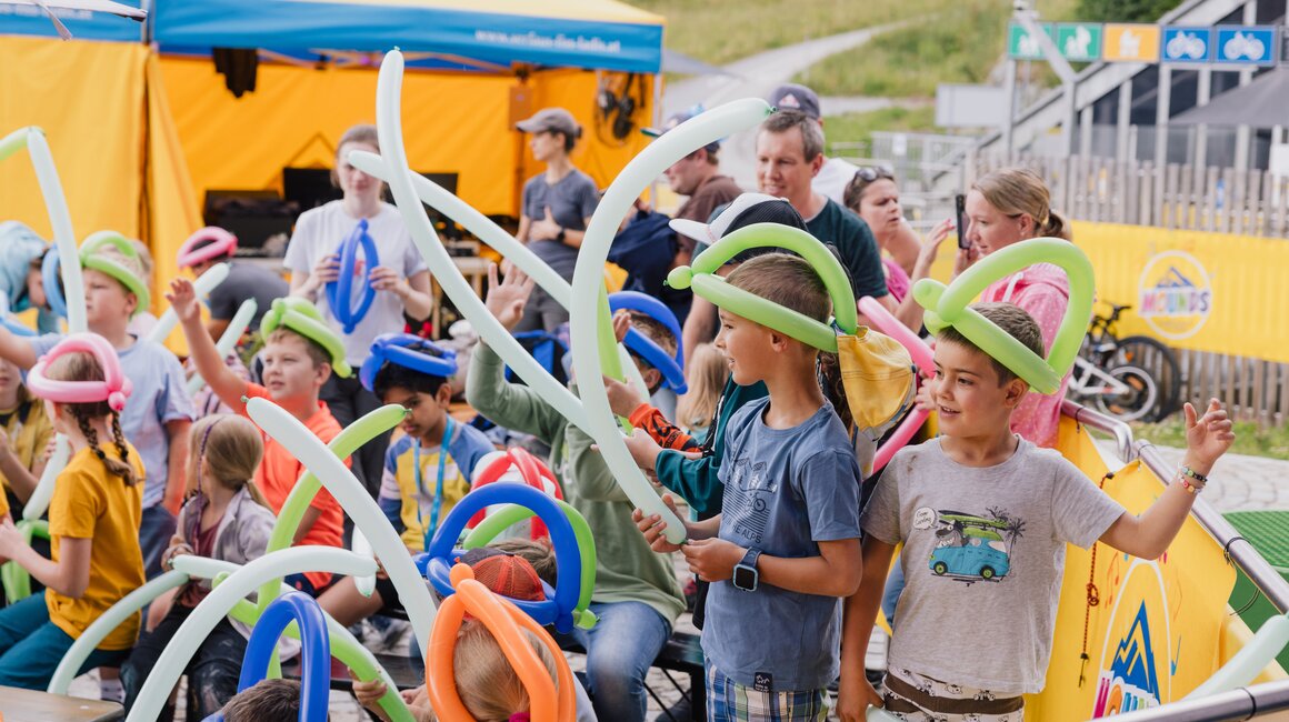 Kinder freuen sich mit bunten Luftballons bei einer Veranstaltung.