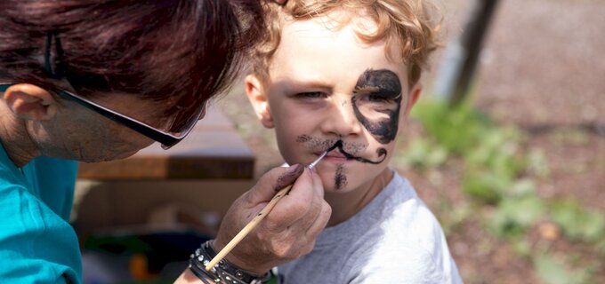 Ein Junge erhält ein Piraten-Make-up von einer Frau.